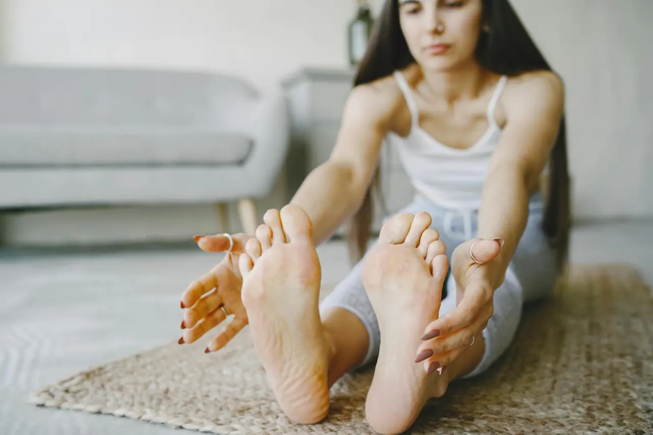 Young woman stretching on a yoga mat indoors, representing post-workout flexibility work.