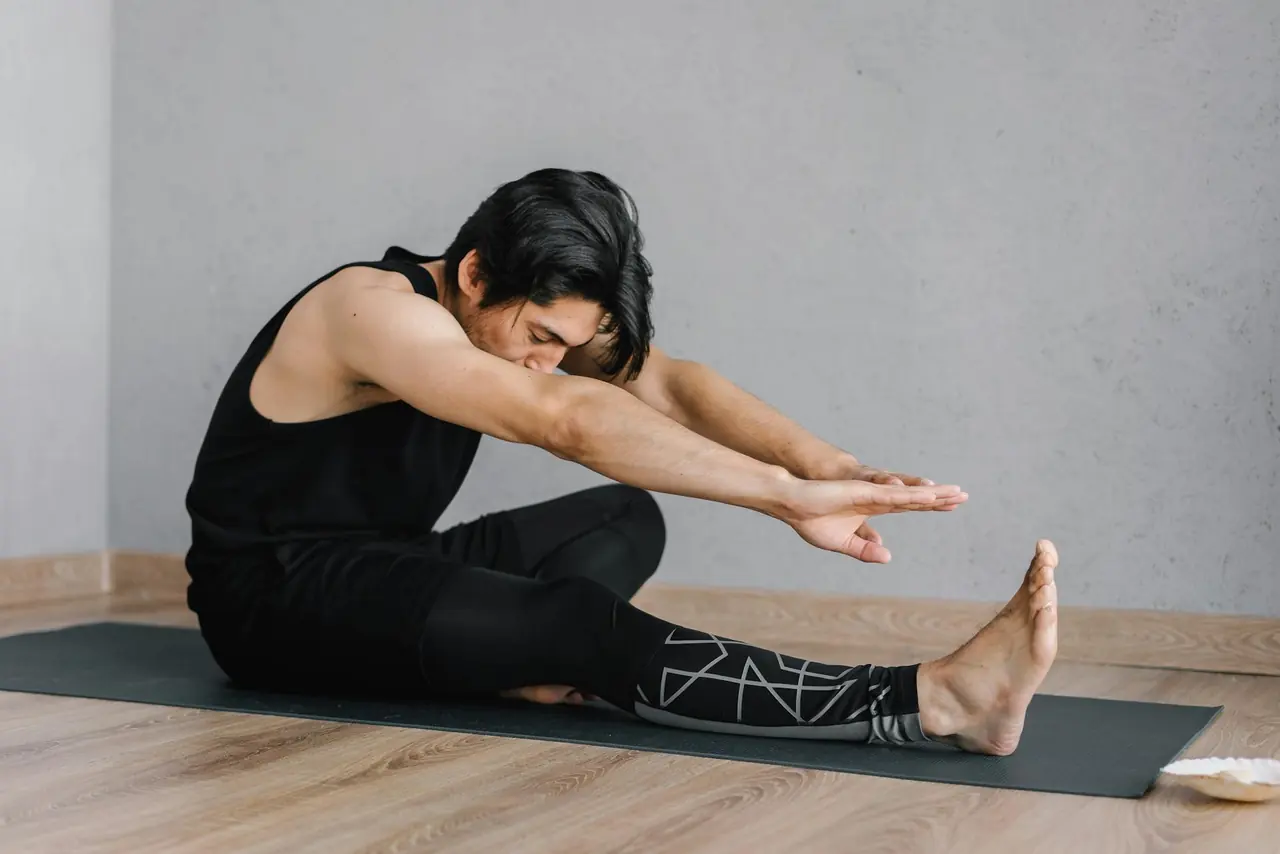 Adult man stretching on a mat in a calm indoor setting after exercise.