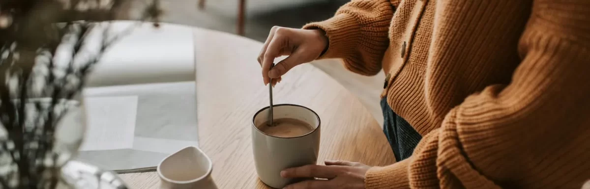Woman stirring coffee in a cozy home setting, representing a daily coffee ritual.