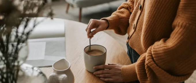 Woman stirring coffee in a cozy home setting, representing a daily coffee ritual.