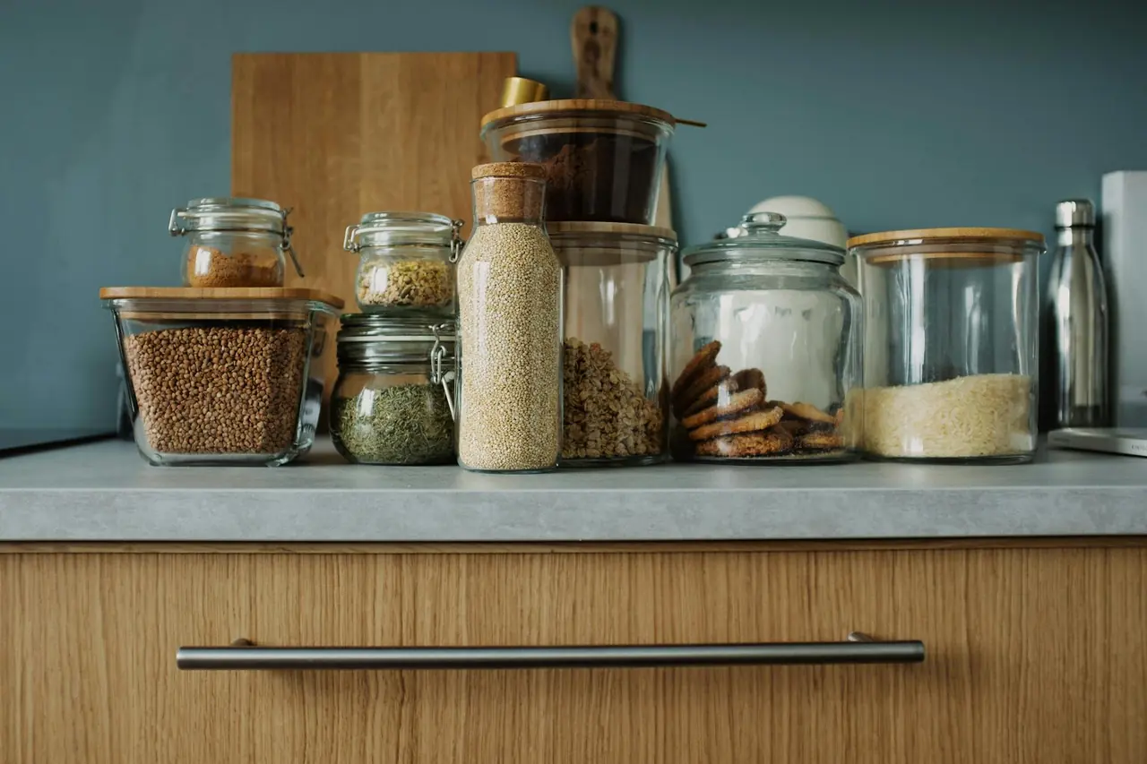Kitchen ingredients stored in clear glass jars on a wooden counter, representing simple food storage and organization.