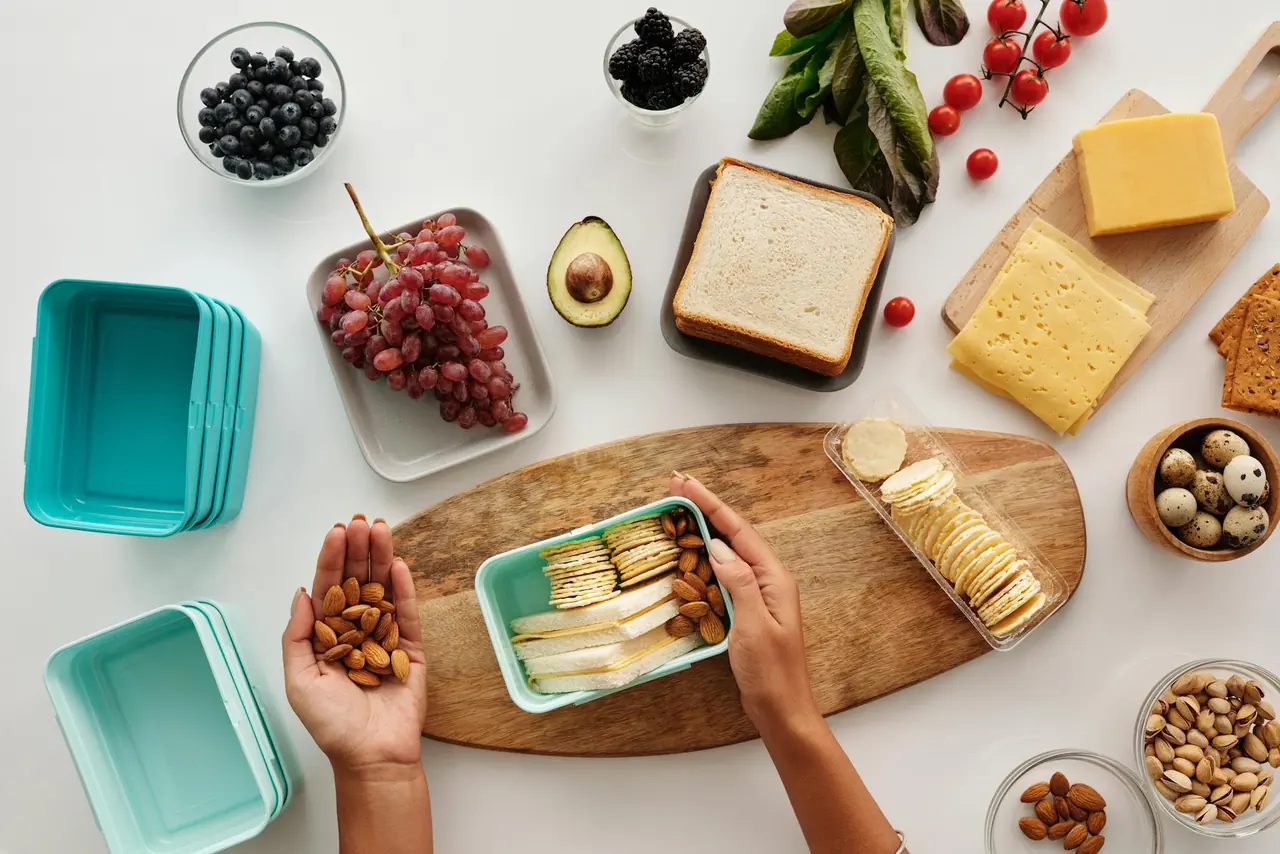 Flat lay of fresh ingredients like fruit, nuts, and cheese for a healthy lunch prep.