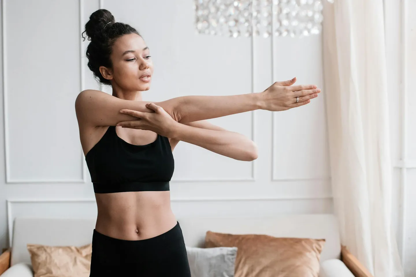 Woman stretching indoors before exercise, representing a warm-up before a home HIIT workout.