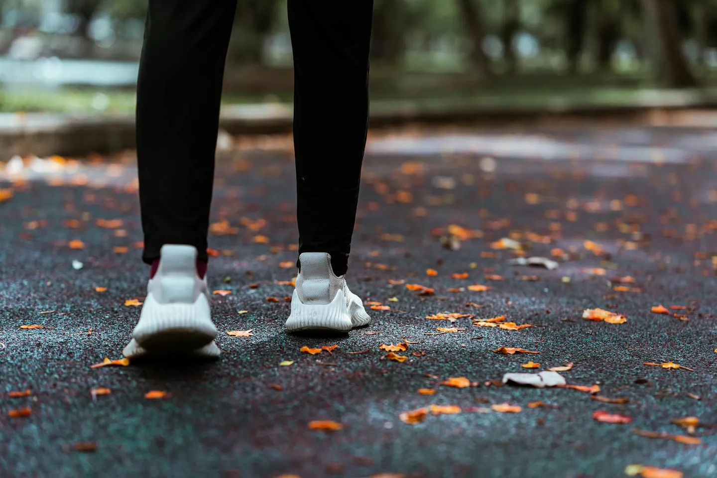 Person walking outdoors in sneakers on a park path, representing simple daily movement and wellness.