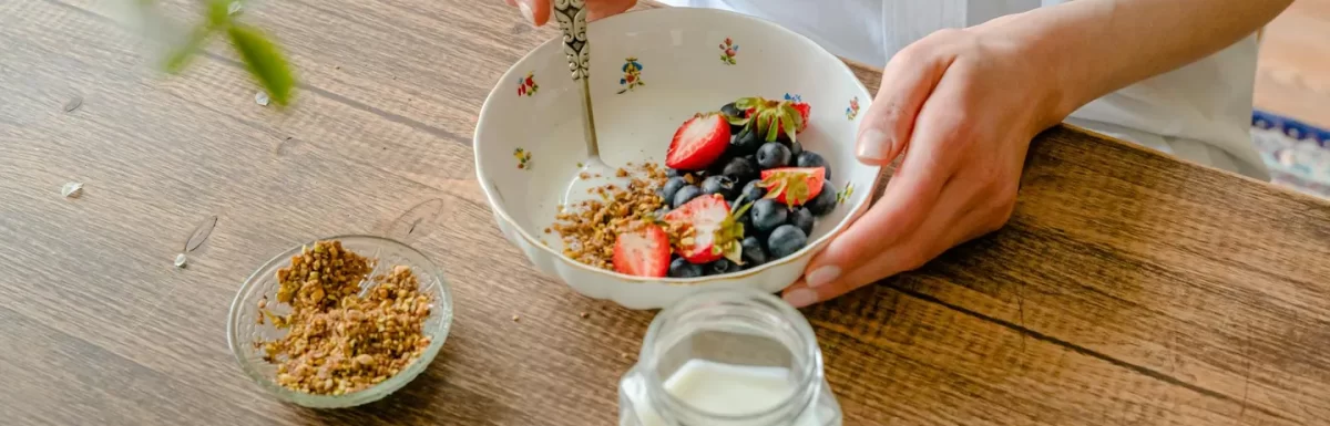 Healthy breakfast bowl with yogurt, berries, and nuts on a wooden table.