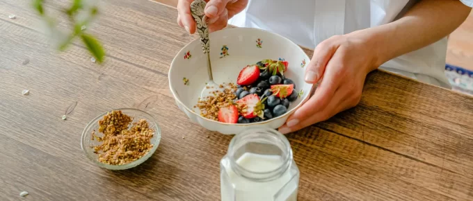 Healthy breakfast bowl with yogurt, berries, and nuts on a wooden table.