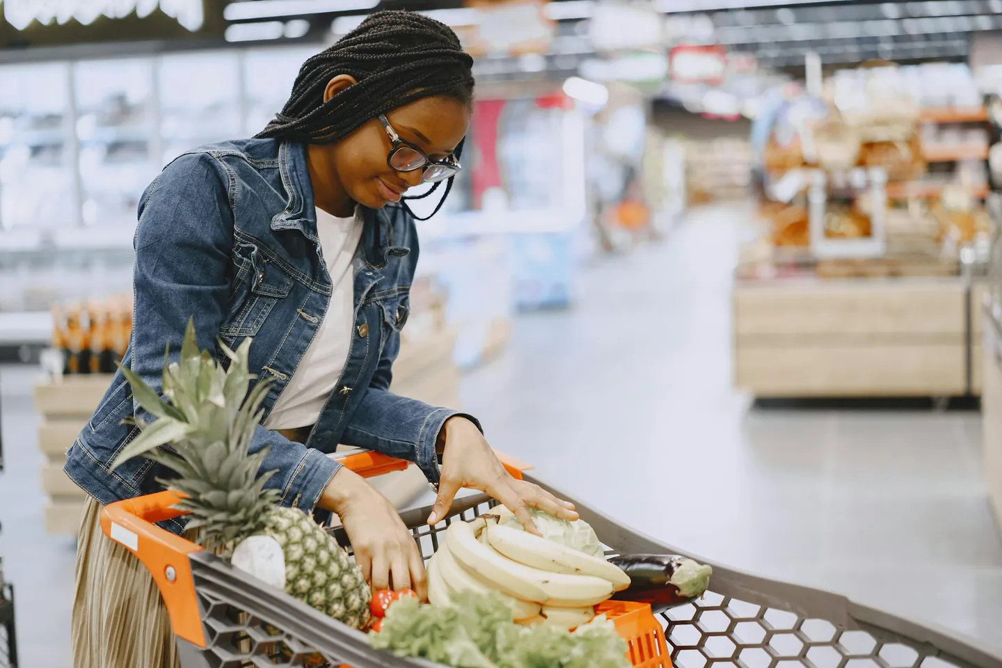 Woman shopping for fresh fruits and vegetables in a grocery store, representing healthy grocery planning.