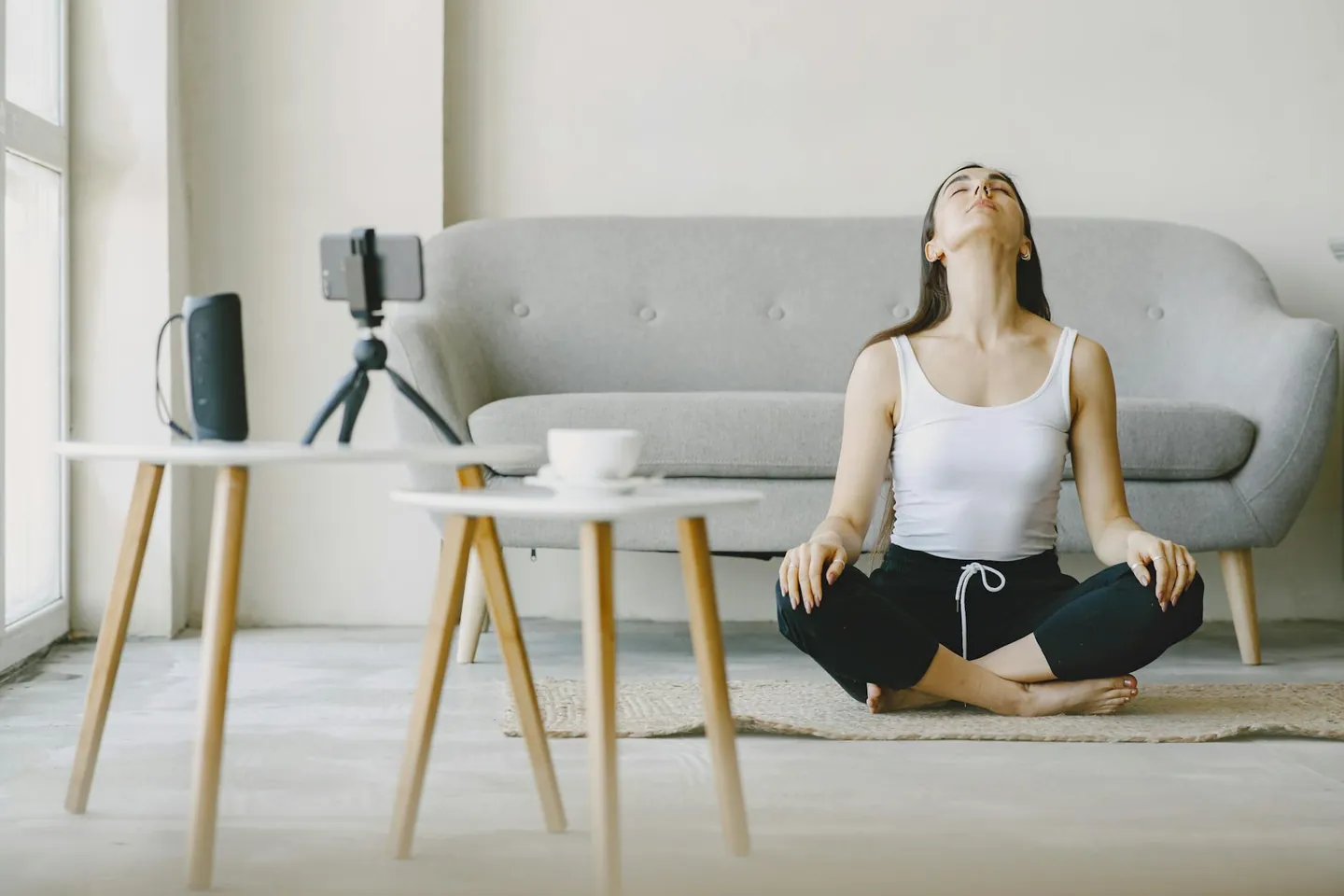 Woman meditating indoors while sitting cross-legged, representing stress management and relaxation.