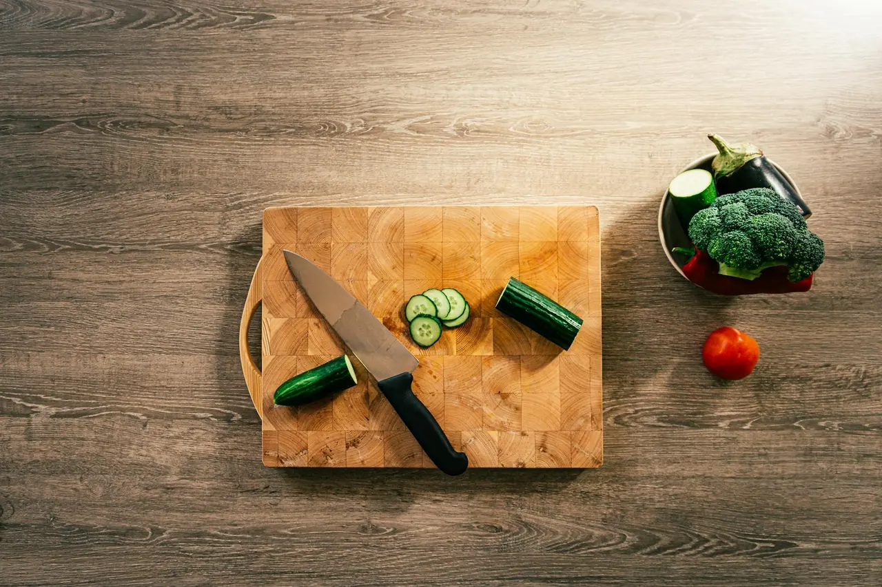 Fresh vegetables and a knife on a wooden board, representing simple meal prep tools.