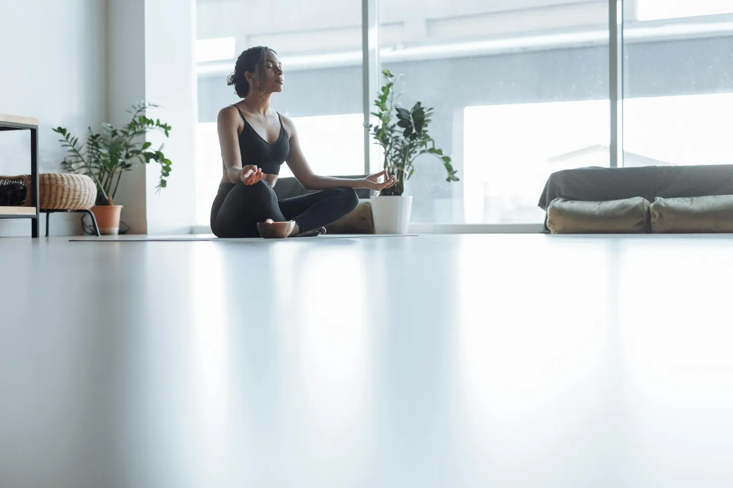 Woman meditating indoors in natural light, representing a calm and focused start to the day.