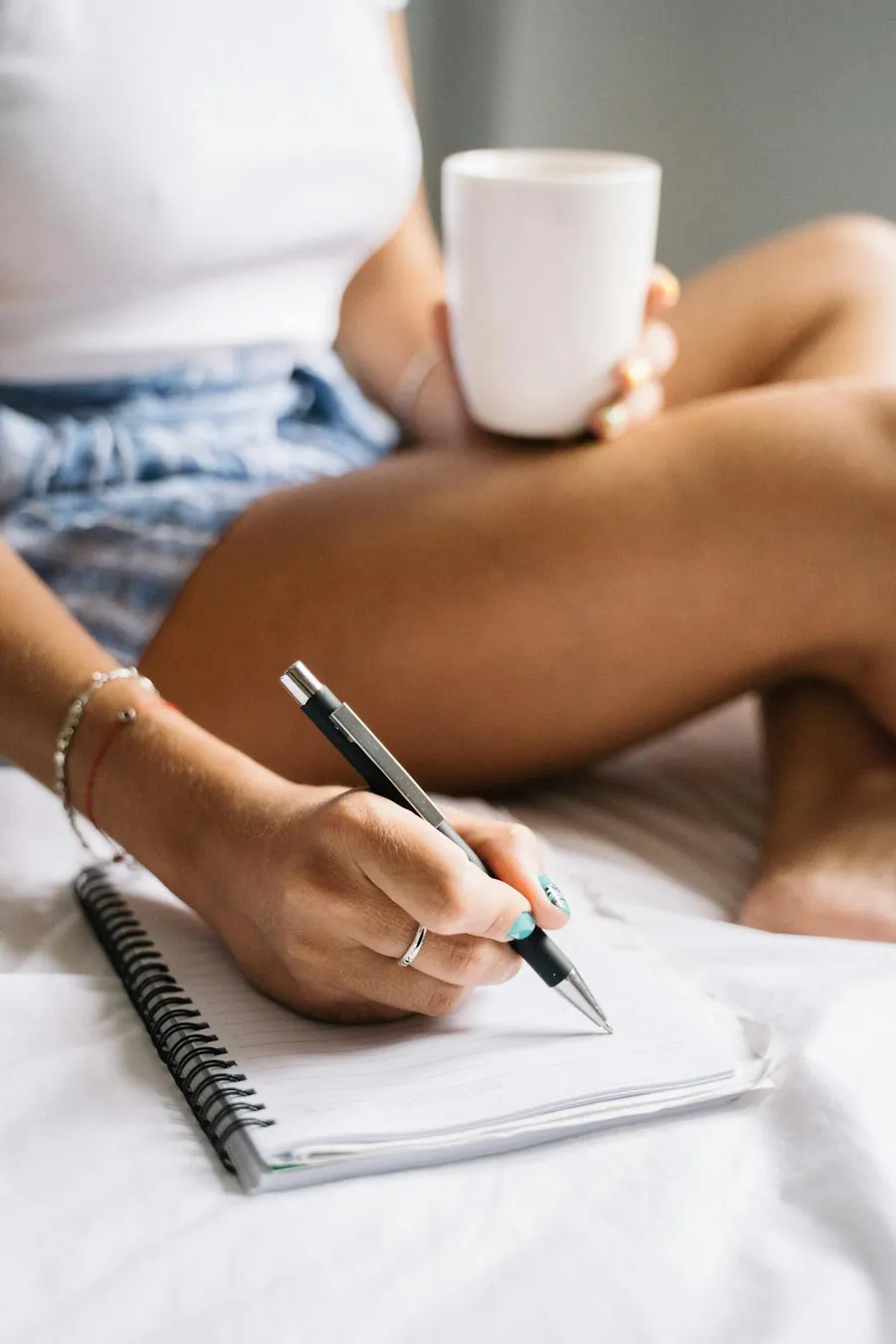 Woman writing in a notebook with coffee during a calm morning routine