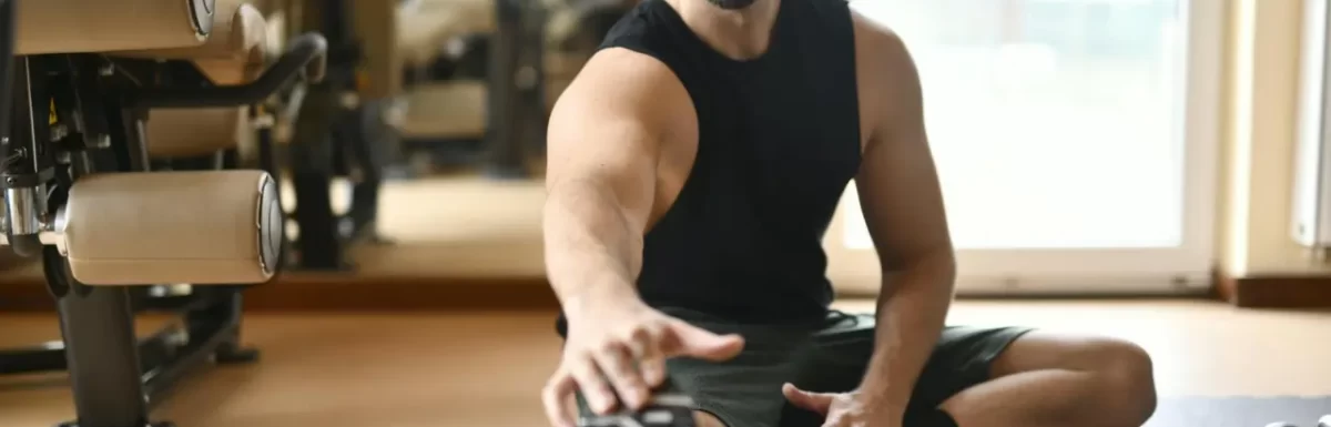 Man in gym clothes stretching on the floor after exercise.