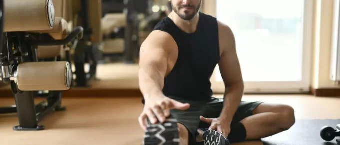Man in gym clothes stretching on the floor after exercise.