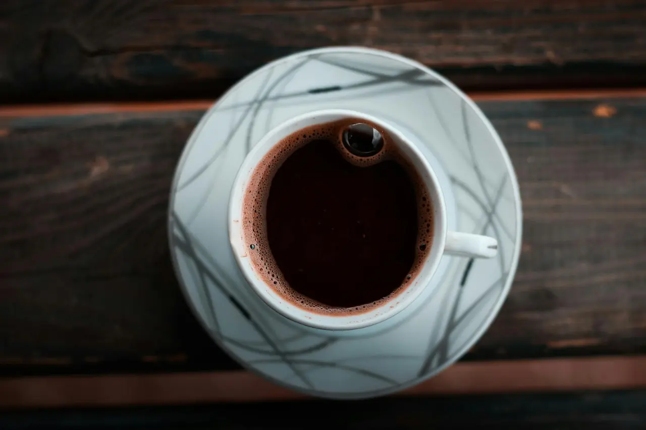 Hot coffee in a cup on a wooden table, representing a simple black coffee habit.