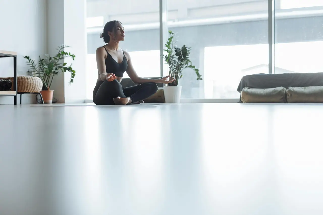 Woman meditating in a calm indoor setting, representing stress management and recovery.