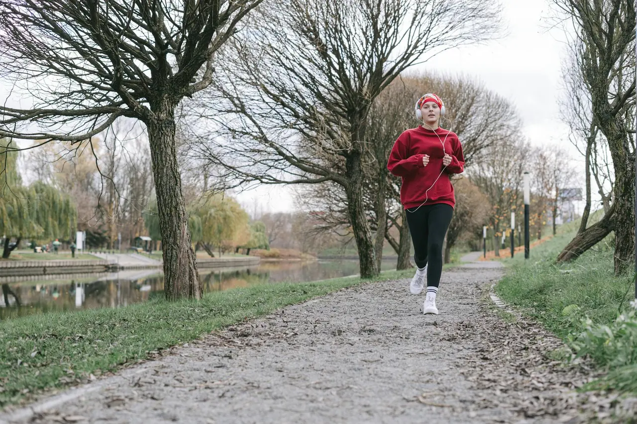 Woman jogging along a tree-lined path, representing movement for energy and daily health.