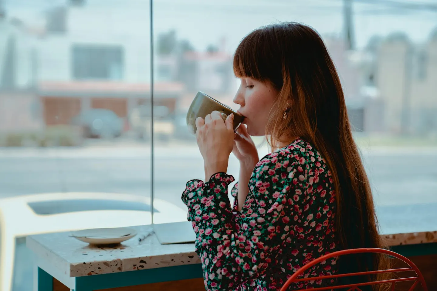Woman drinking coffee in the morning at a café table, representing coffee for focus and enjoyment.