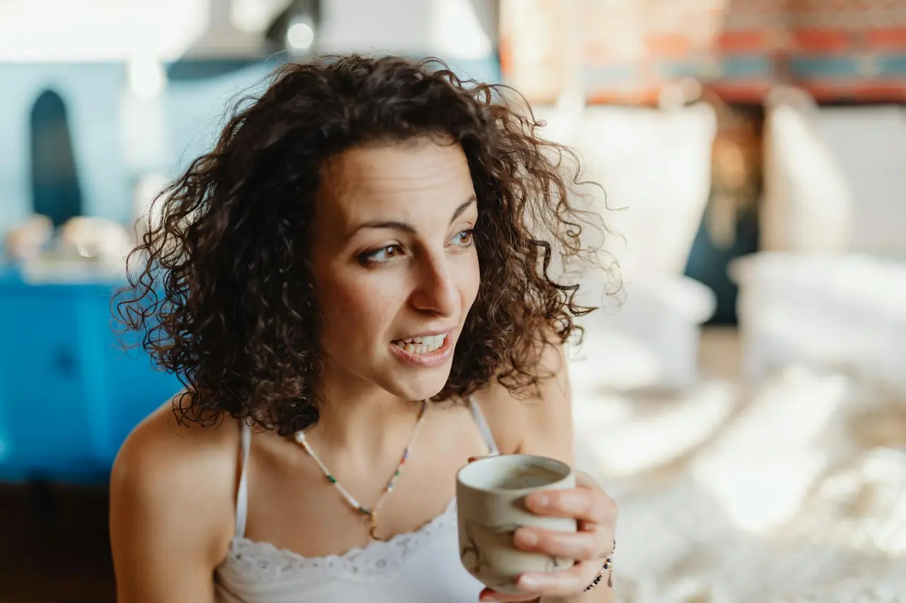 Young woman enjoying coffee in a cozy indoor setting.