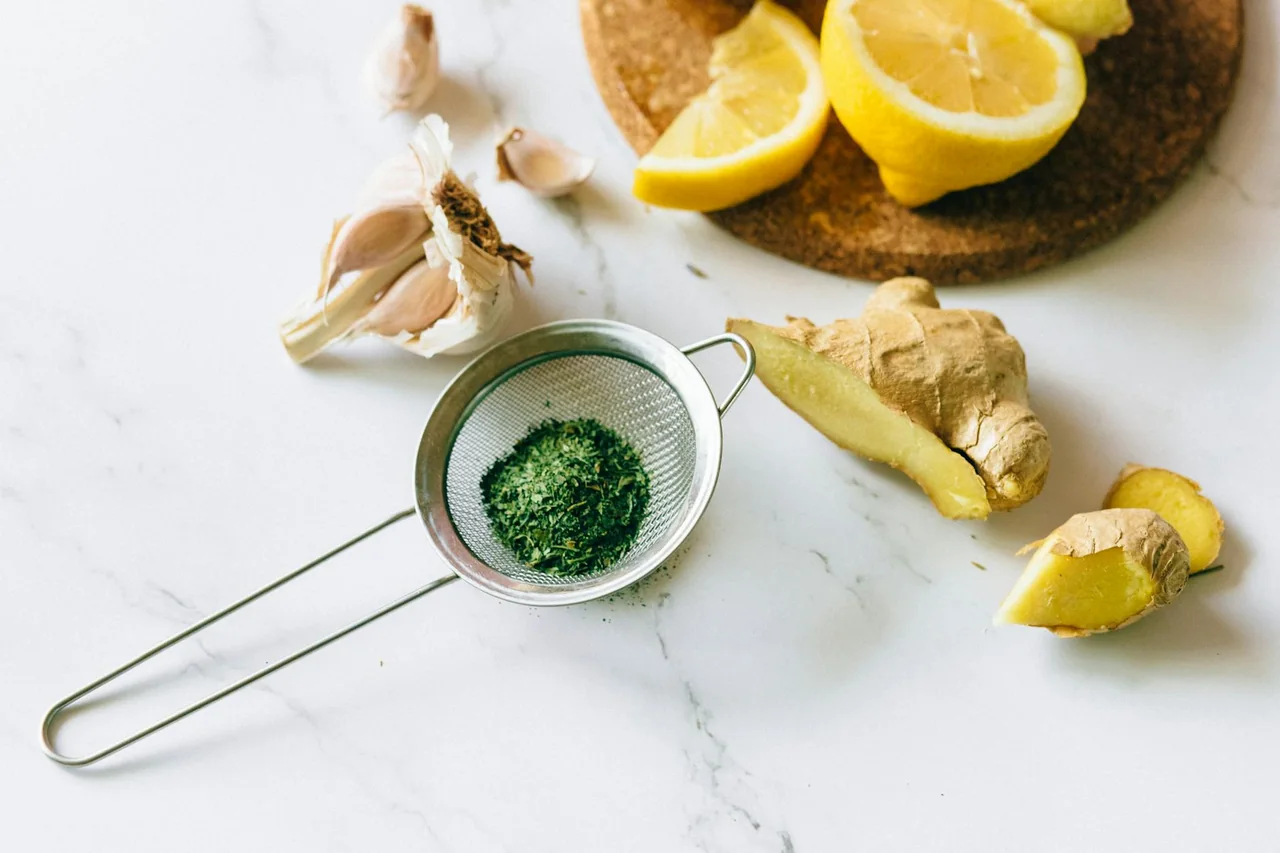 Garlic, ginger, turmeric, and herbs arranged on a kitchen counter