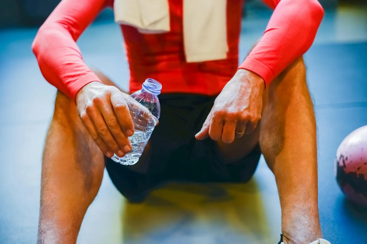 Athlete stretching on a rest day beside a water bottle