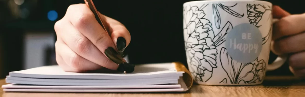 Fresh coffee on a desk beside a notebook in soft morning light