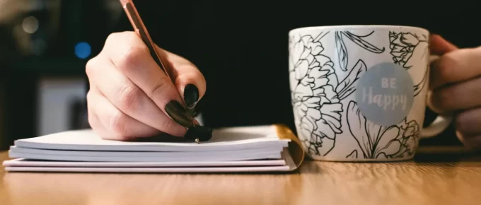 Fresh coffee on a desk beside a notebook in soft morning light