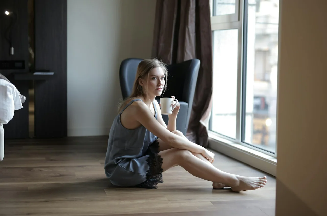 Person drinking coffee near a bright window in the morning