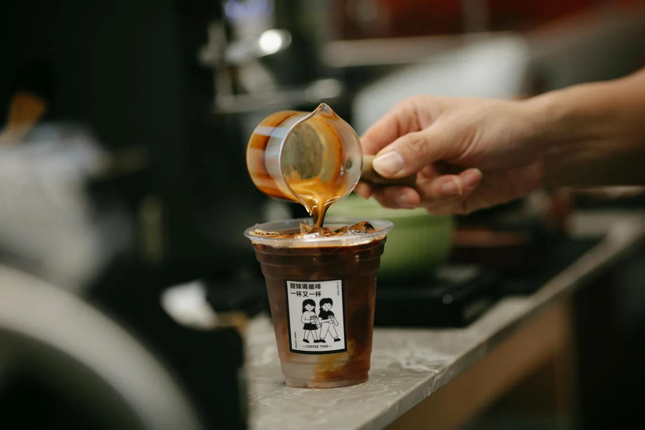 Barista pouring freshly brewed coffee over ice