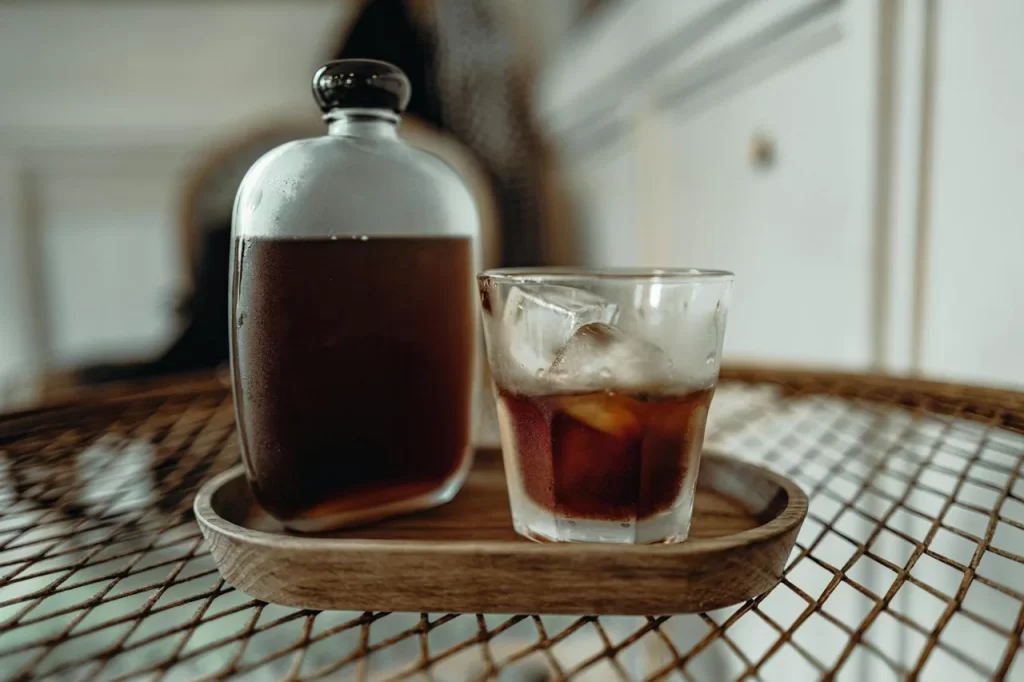 Glass of cold brew coffee with ice beside a bottle