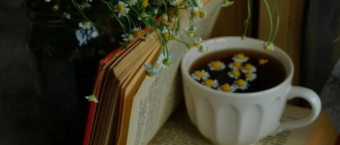 Cup of herbal tea on a bedside table beside a book and warm lamp