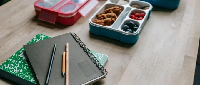 Packable healthy lunch containers beside a laptop and notebook