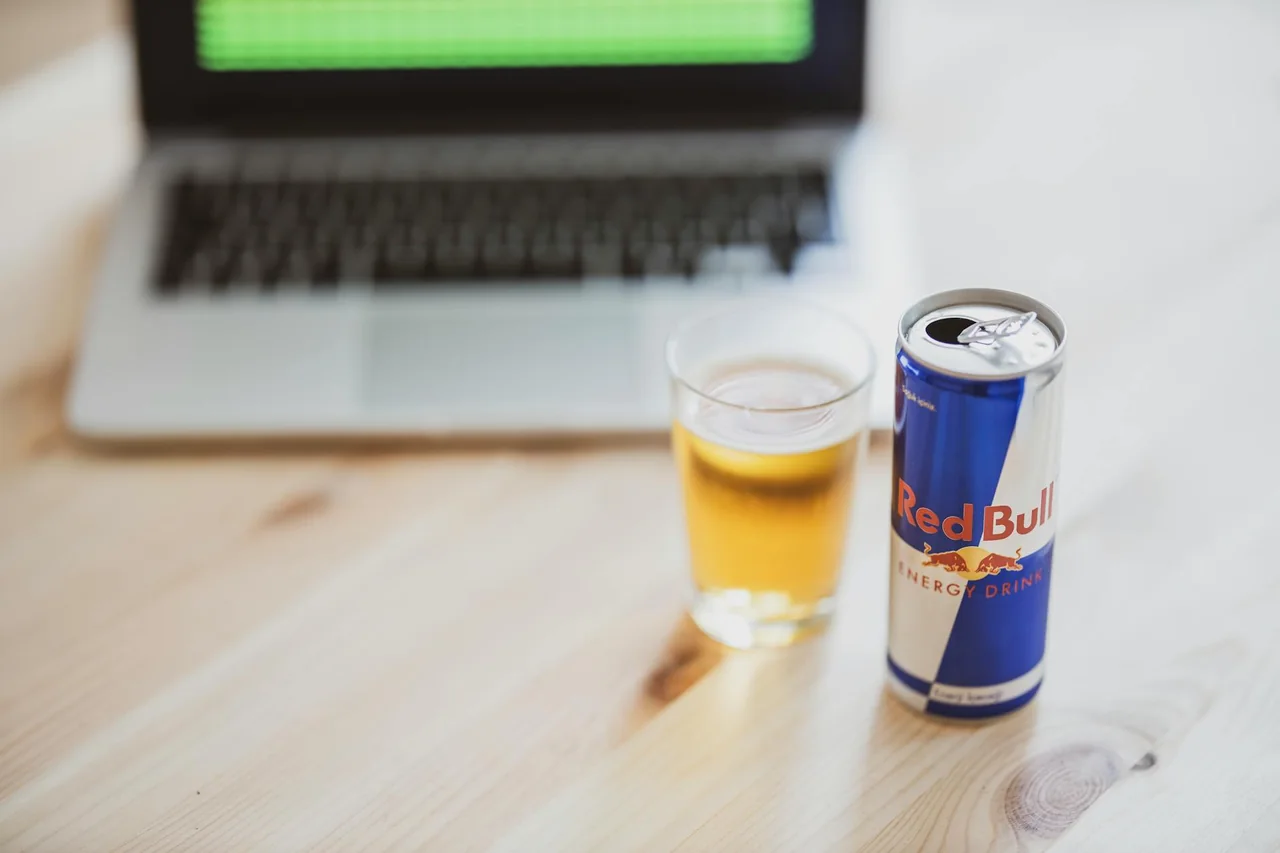 Energy drink cans on a desk beside a keyboard