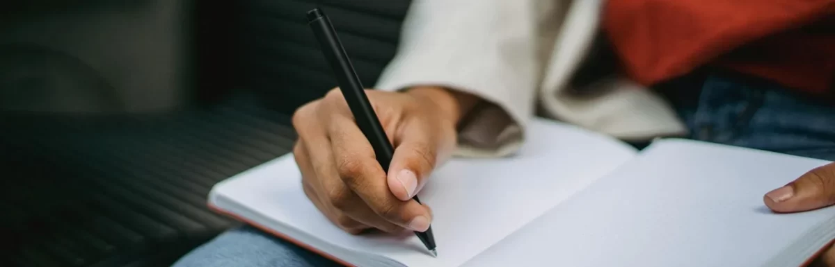 Person writing a short daily habits checklist in a notebook