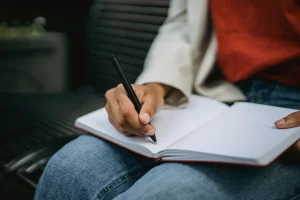 Person writing a short daily habits checklist in a notebook
