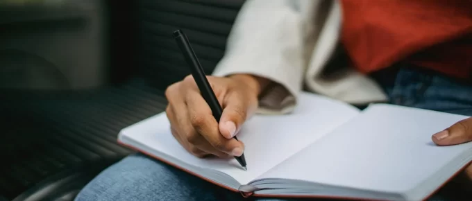 Person writing a short daily habits checklist in a notebook