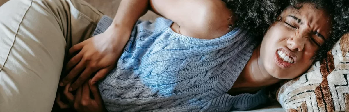 Woman resting on a sofa with a hand on her stomach in soft natural light