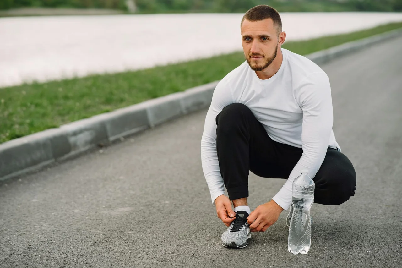 Person getting ready for a workout with shoes and a water bottle