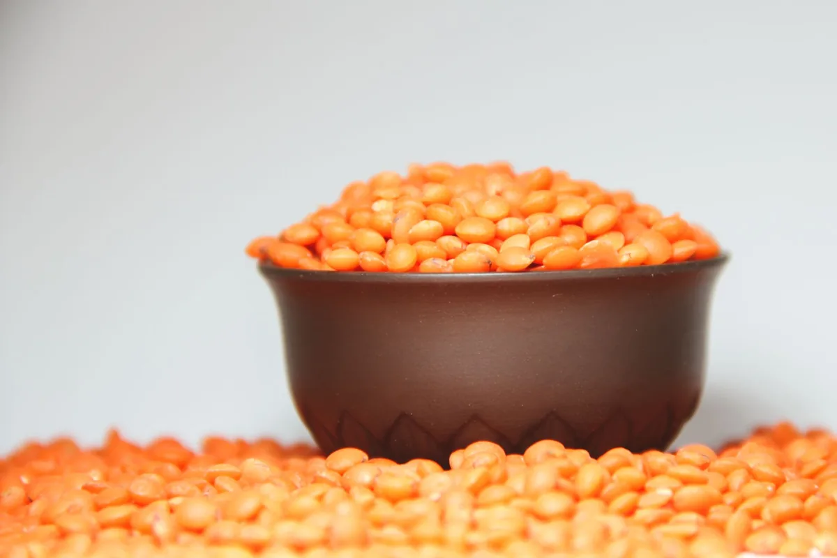 Red lentils in a bowl with lentils scattered around it