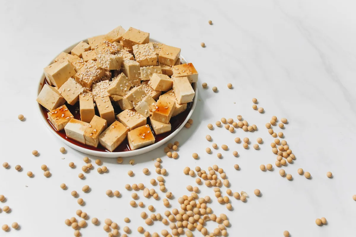 Cubed tofu on a plate beside dried soybeans