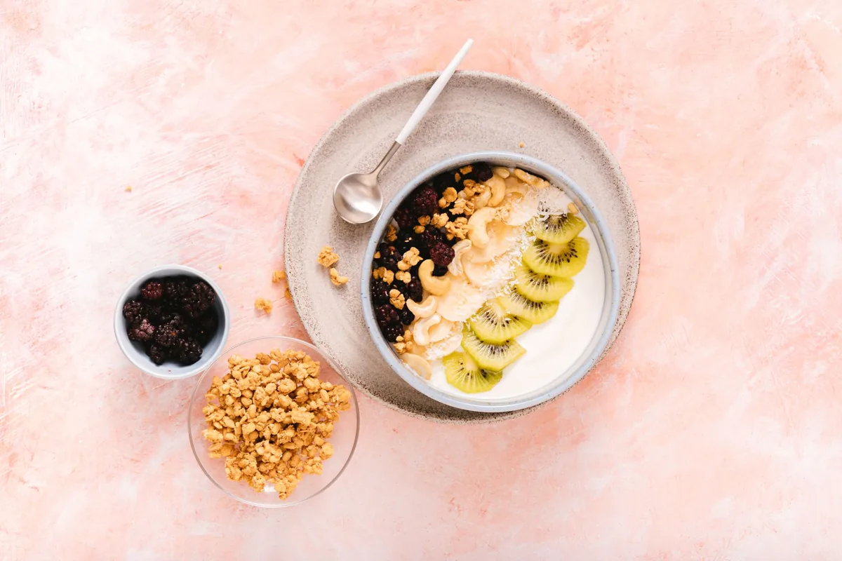 A yogurt bowl topped with kiwi, banana, berries and granola