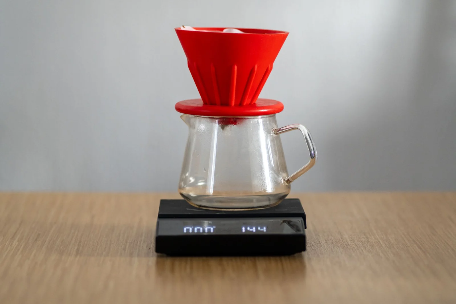 Red coffee dripper and glass carafe sitting on a digital scale