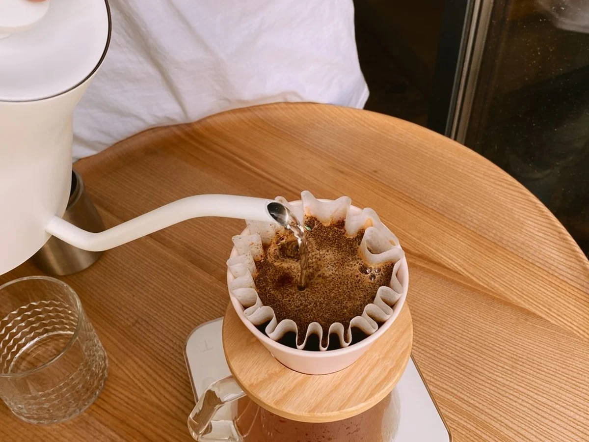 Hot water poured over a bed of coffee in a paper filter.