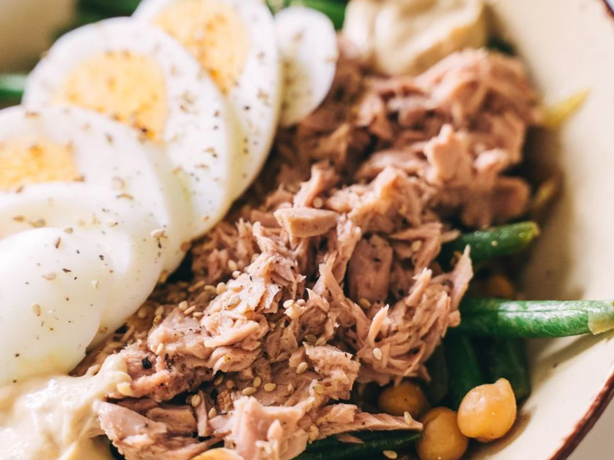 Tuna, halved boiled eggs, green beans and chickpeas in a salad.