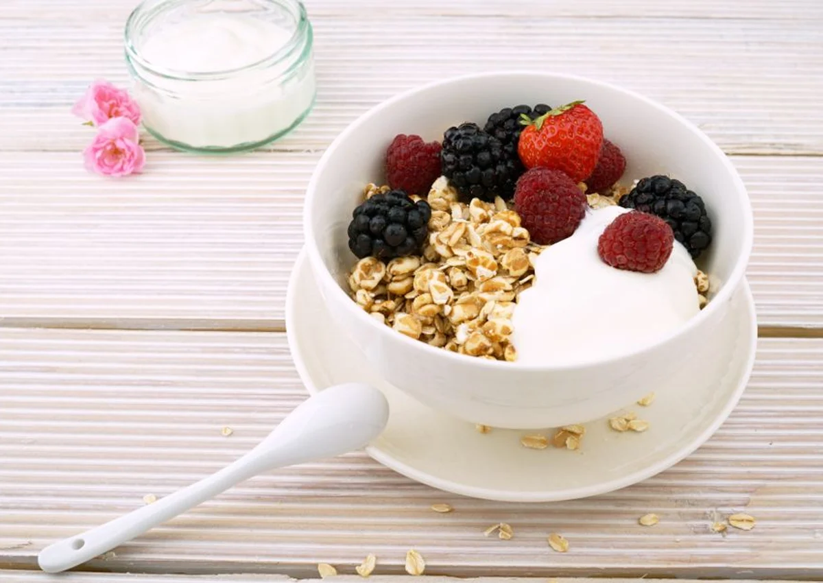 A white breakfast bowl with yogurt, oats and mixed berries.